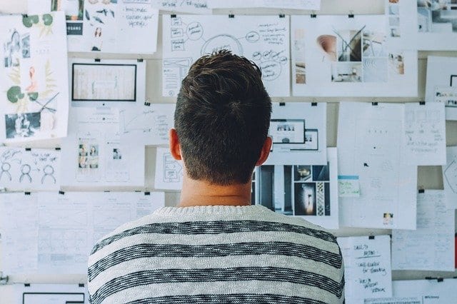 man looking at a board of diagrams and pictures solving a problem